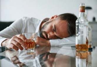 Conception of addiction. Upset young man drinker alcoholic is indoors